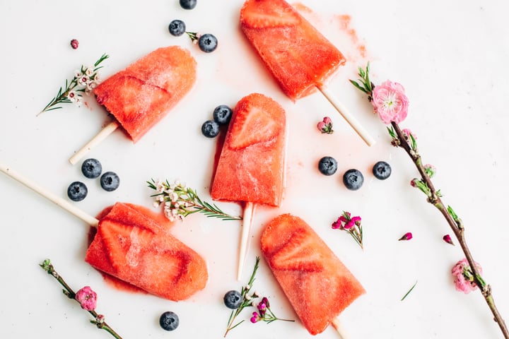 champagne strawberry popsicles with blueberries surrounding it 