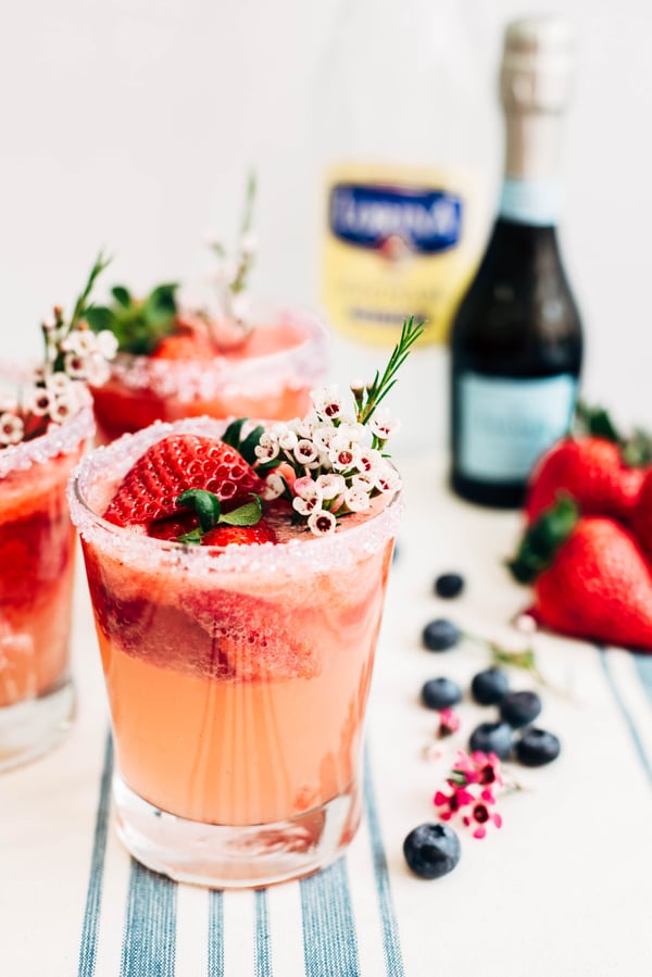 strawberry lemonade spritzer in a glass with a salted rim and garnished with edible flowers and strawberries