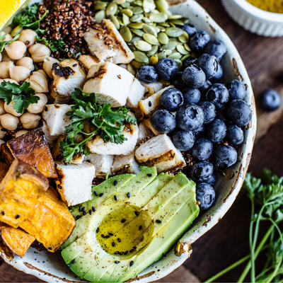 nourish bowl with avocado, blueberries, chicken, pumpkin seeds, and chickpeas