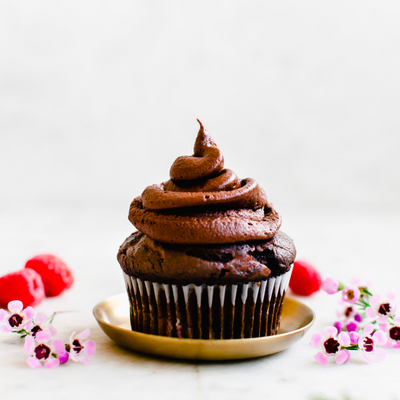 chocolate cupcake with raspberries and flowers on the side