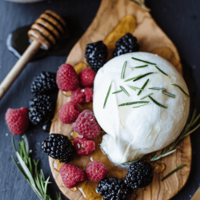 burrata with berries on the side topped with honey 