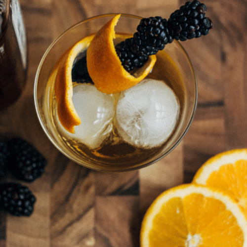 bourbon cider garnished with an orange peel and blackberries