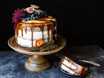 blackberry chocolate cake with topped with frosting, caramel, and berries