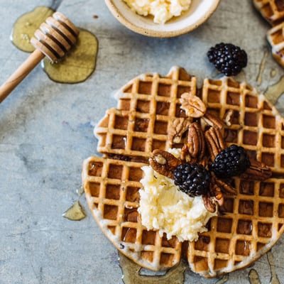 waffle topped with syrup, blackberries, and pecans