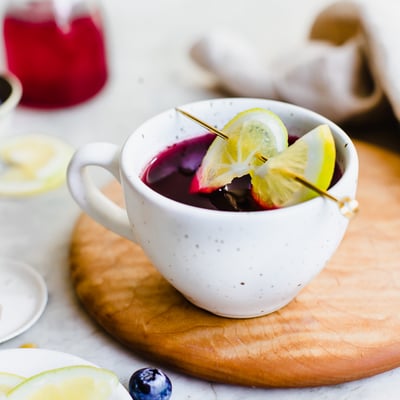 Blueberry Hot Toddy with lemon slices on a toothpick