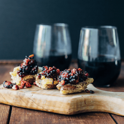 crispy artichokes topped with blackberry pesto on a wooden cuttingboard