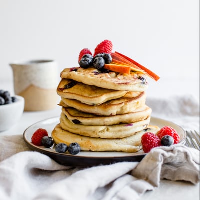 tall stack of pancakes topped with mixed berries