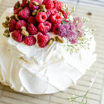 pistachio pavlova with whipped cream topped with raspberries and flowers