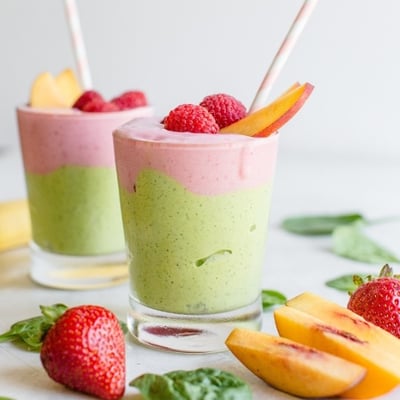 a green and pink berry smoothie in a glass