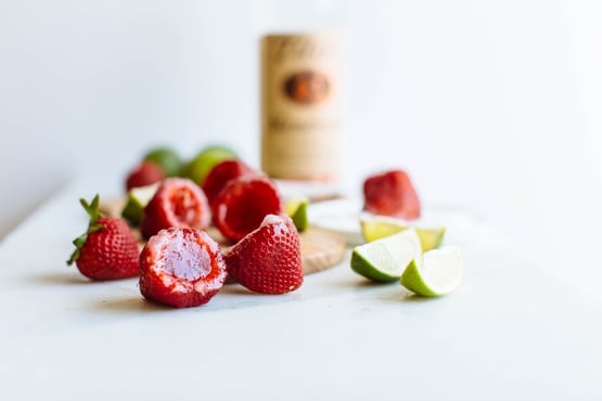 hollowed strawberries being used as a glass to take a vodka shot from 