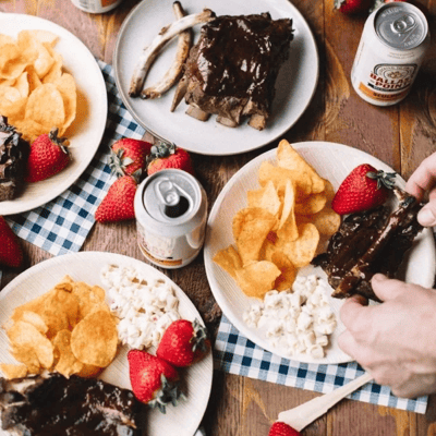 bbq ribs served with a side of strawberries, potato chips, and potato salad