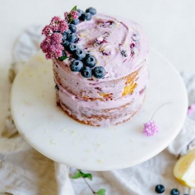 blueberry lemon olive oil cake topped with lavender frosting, blueberries, and flowers