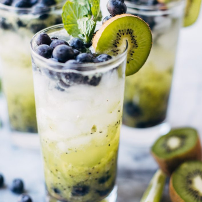 blueberry kiwi mojito garnished with a slice of kiwi, blueberries, and mint leaves