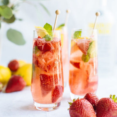 fresh herb berry cocktail filled with strawberries and topped with a slice of lemon and mint leaves
