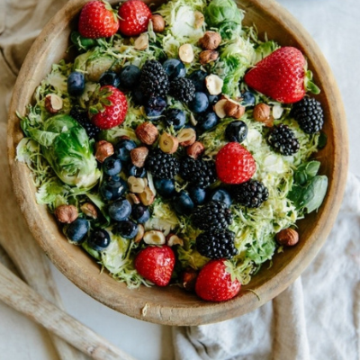 shaved brussels sprouts with berries in a wooden bowl