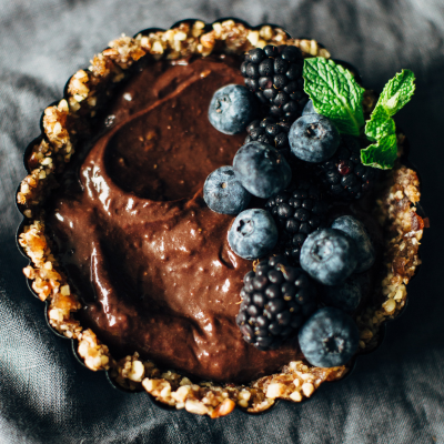 pecan crust tart topped with chocolate blackberries, blueberries, and mint leaves