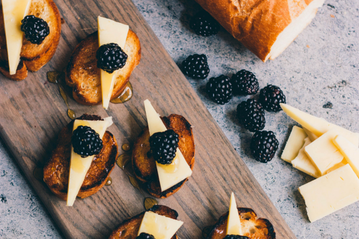 pieces of bruschetta  topped with cheese, honey, and blackberries 