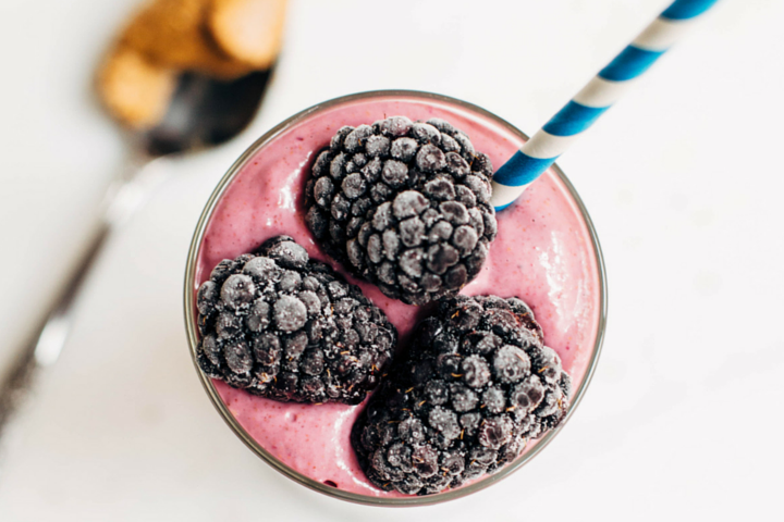 berry smoothie topped with blackberries and a striped blue straw