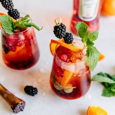 berry aperol spritz garnished with orange slices, blackberries, and mint leaves