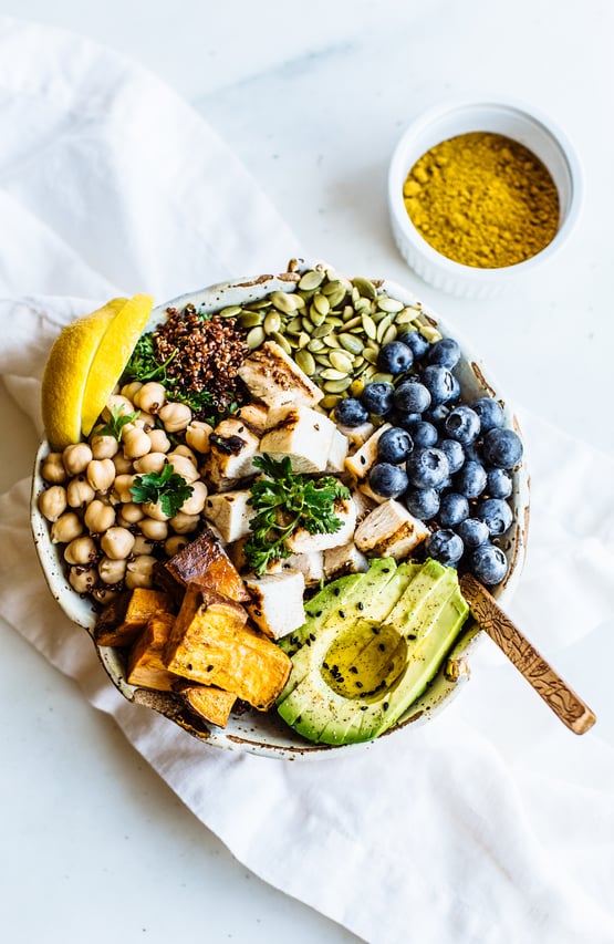 a bowl with avocado, blueberries, garbanzo beans, grilled chicken, and pumpkin seeds