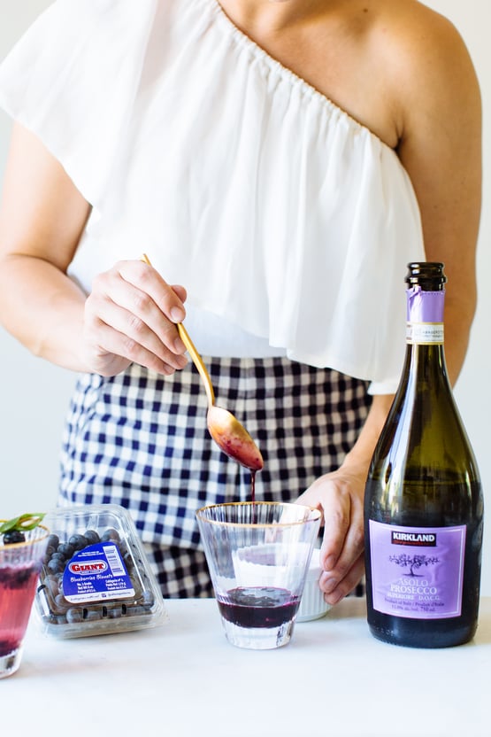 someone preparing a blueberry basil bellini 