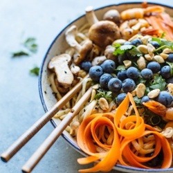 noodles with blueberries, carrots, mushrooms, and peanuts with chopsticks on the side