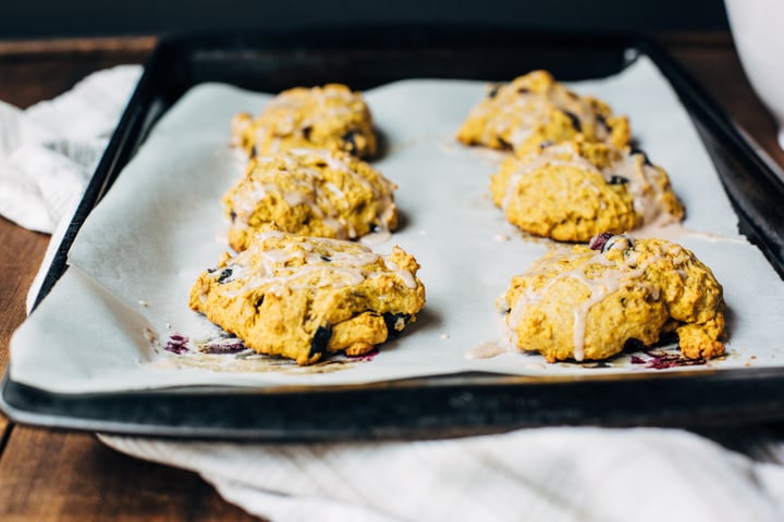 blueberry pumpkin scone drizzled with a blueberry glaze on a cooking sheet