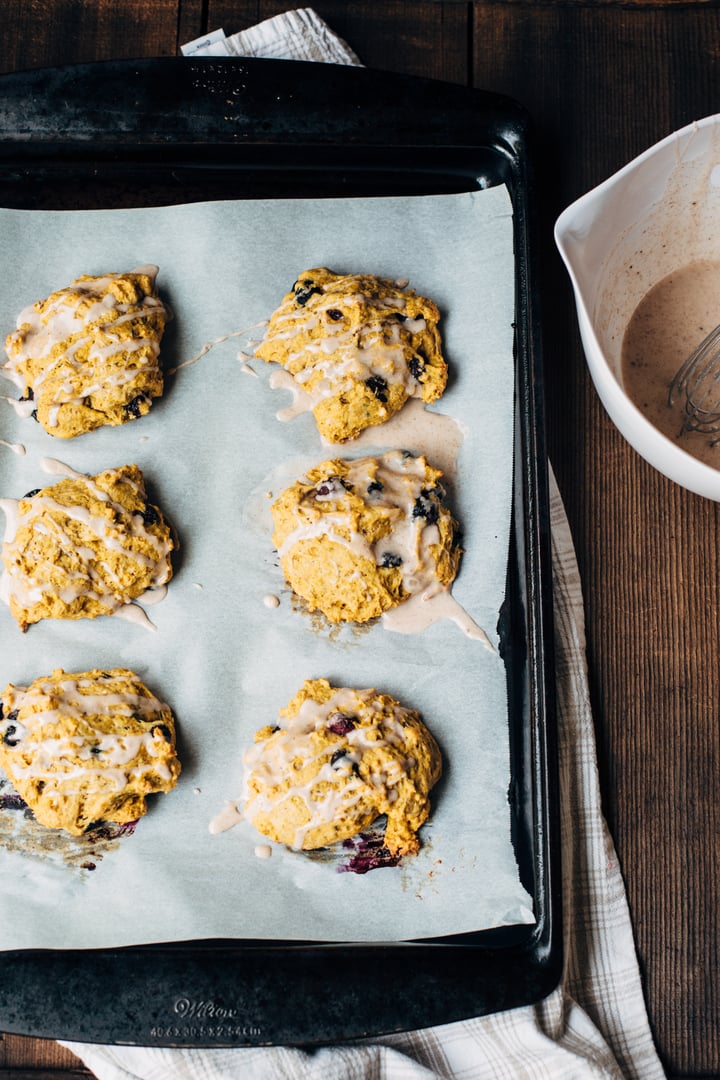 blueberry pumpkin scone drizzled with a blueberry glaze on a cooking sheet