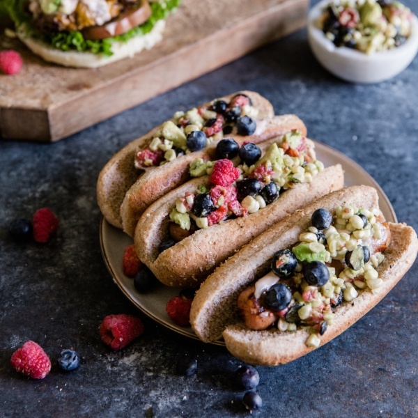 hot dog topped with a corn salsa and berries