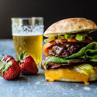 a hamburger with strawberries on the side and a drink