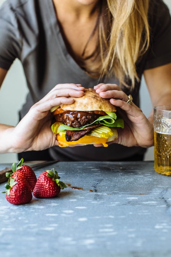 someone holding a hamburger with strawberry bbq sauce