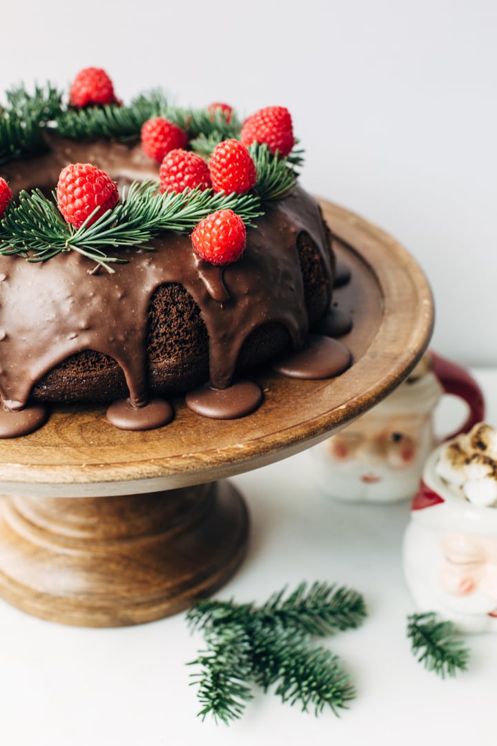 chocolate budnt cake topped with raspberries on cake stand