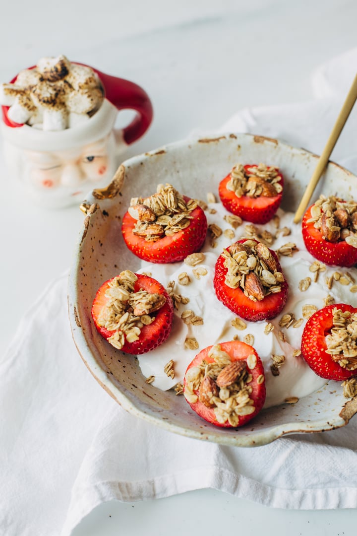 yogurt topped with granola stuffed strawberries and a Santa clause mug on the side