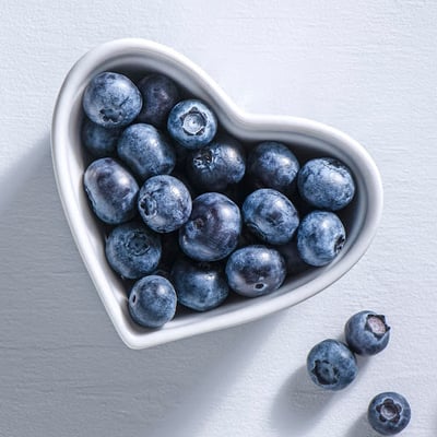 a heart shaped bowl with blueberries in it