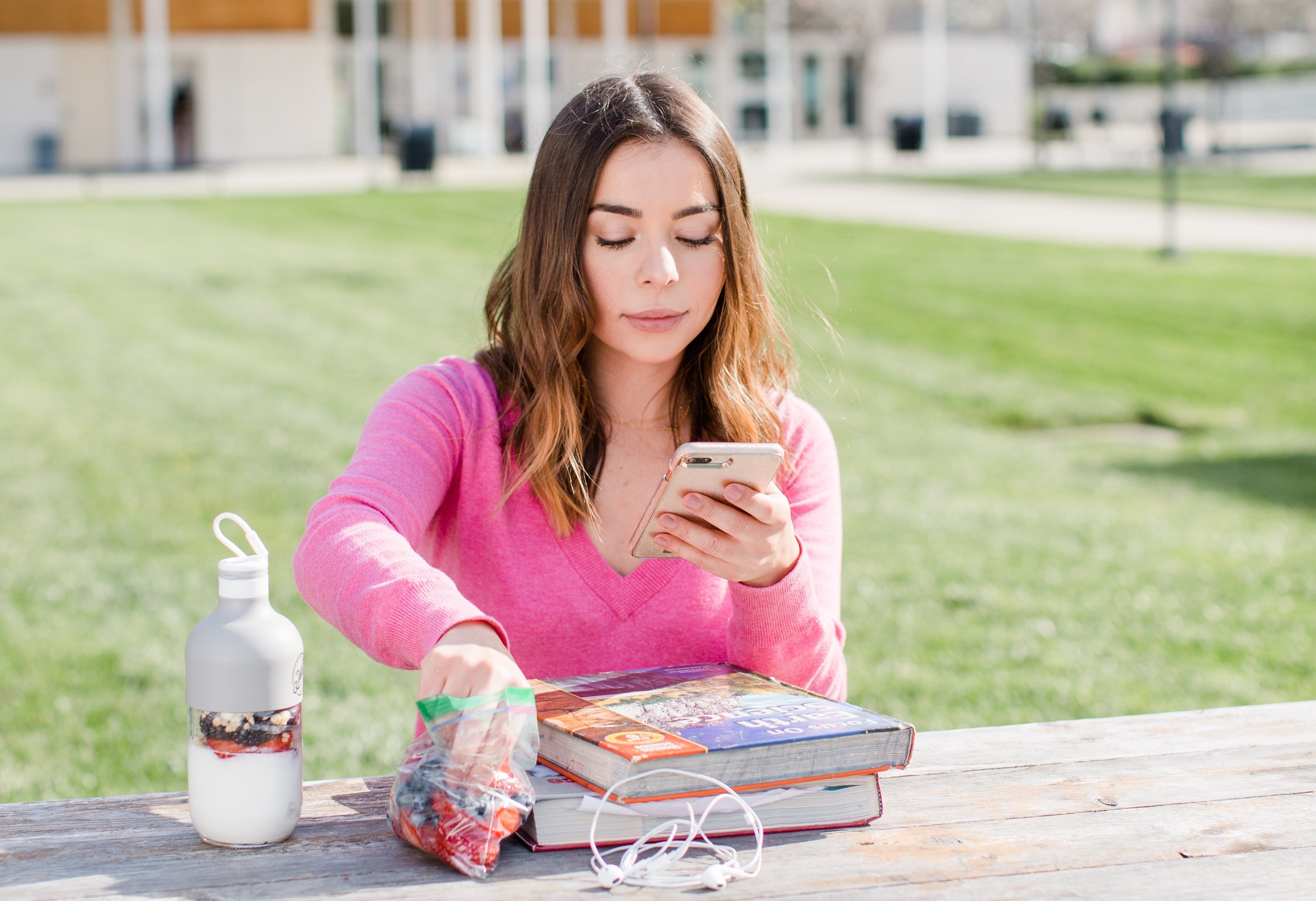 someone sitting at a picnic table reaching into a bag with fresh berries