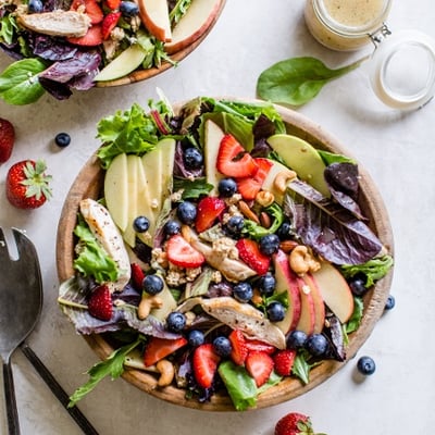 salad topped with berries, apples, cashews, and chicken 