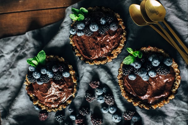 chocolate tart topped with blueberries, blackberries, and mint leaves
