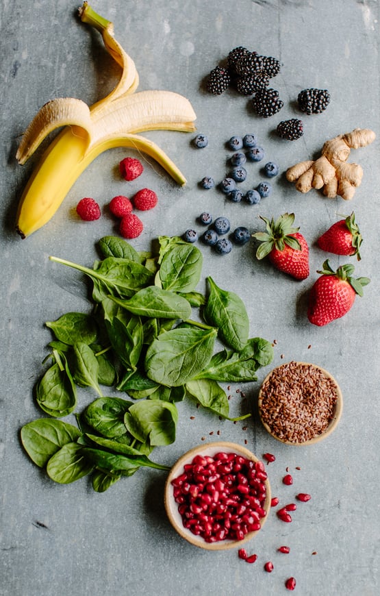 Spinach, pomegranate seeds, berries, a banana, flax seeds, and ginger