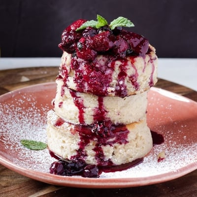 A fluffy stack of japanese pancakes topped with a berry compote