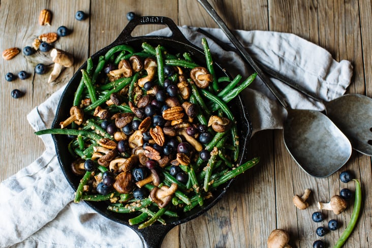 green beans with blueberries, shitake mushrooms, and pecans in a cast iron skillet