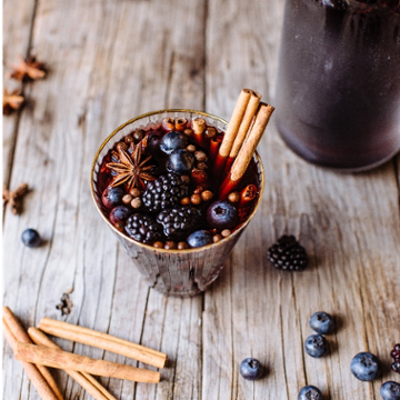 spiced holiday sangria topped with blueberries and a cinnamon stick