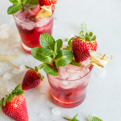 ginger kombucha cocktail with strawberry syrup and topped with strawberries and mint leaves 