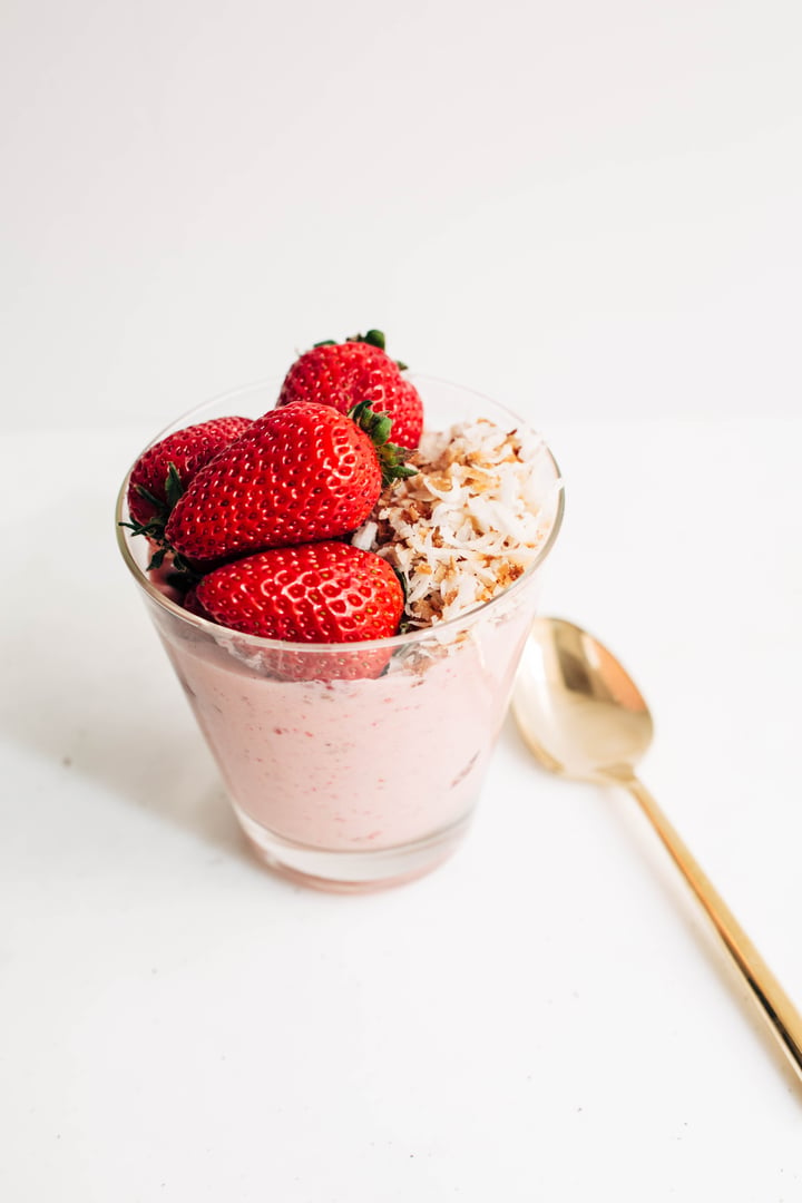 berry smoothie topped with strawberries and shredded coconut