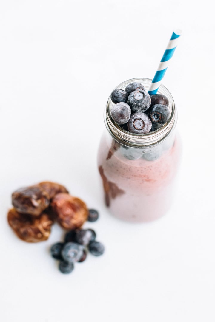 smoothie in a glass milk jar topped with a blue striped straw