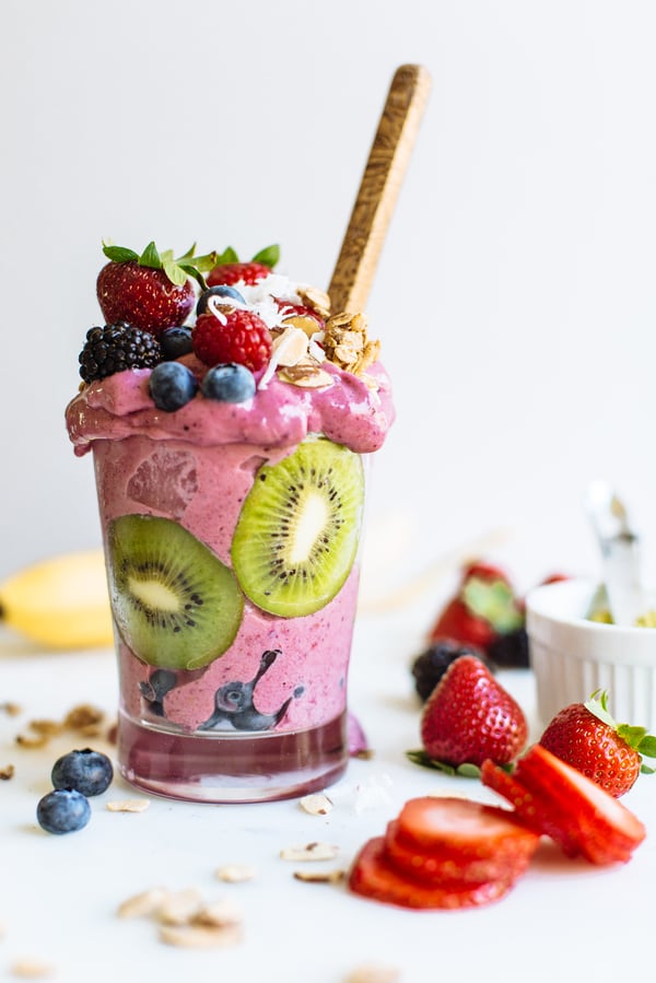 smoothie in a glass with kiwi, berries, and sliced almonds