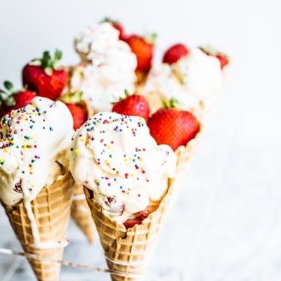 ice cream in a waffle cone topped with strawberries and sprinkles