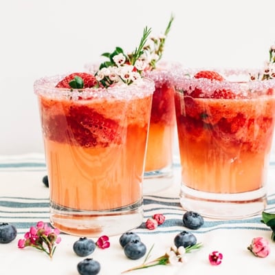 strawberry lemonade spritzer in a glass with a salted rim and garnished with edible flowers and strawberries