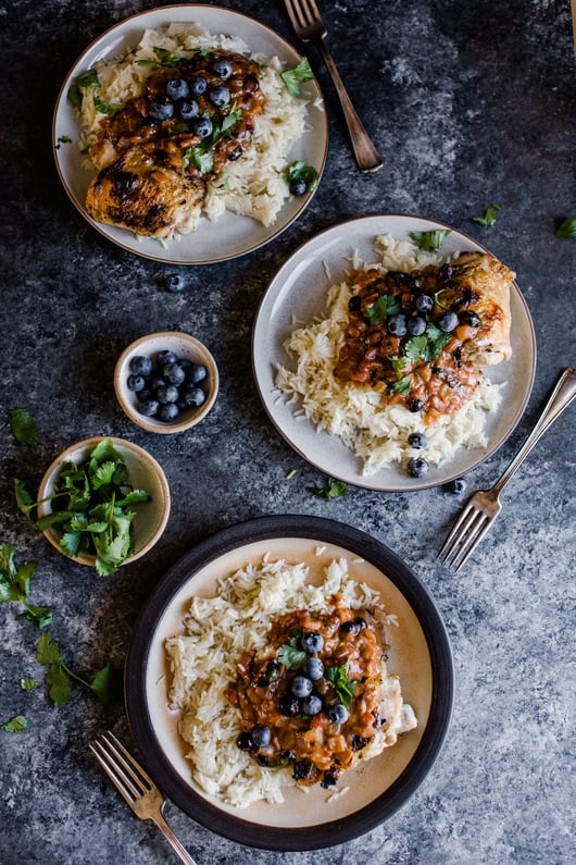 3 plates of tikka masala on rice topped with blueberries