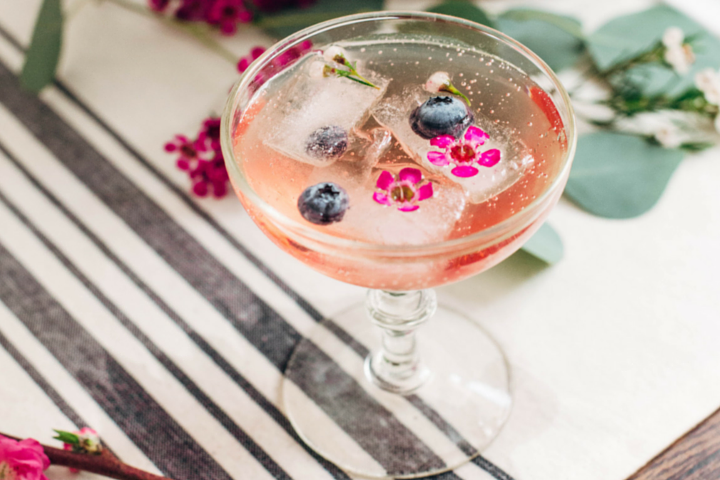 berry and flower edible ice cubes in a glass of champagne
