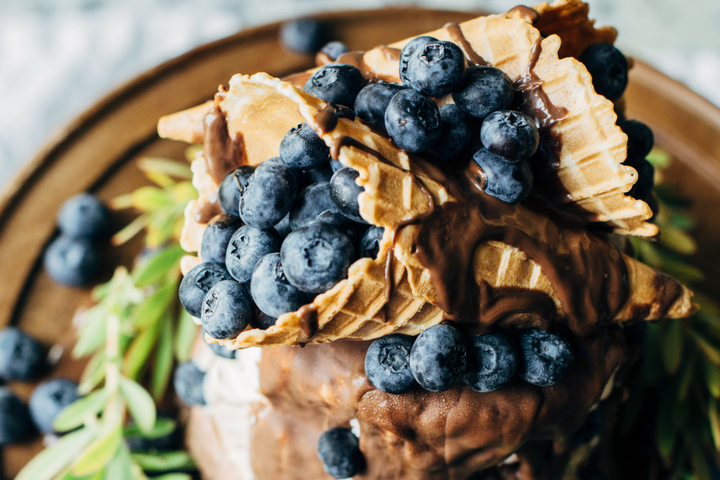 ice cream cake topped with a waffle cone, chocolate drizzle, and blueberries